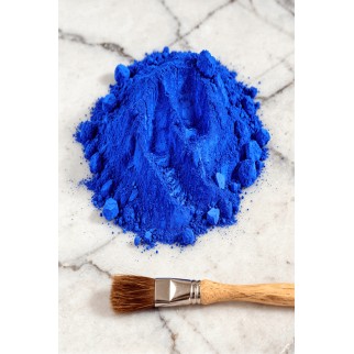 Poudre pigment bleu outremer en tas sur surface claire avec pinceau à côté, usage décoratif pour béton ciré.